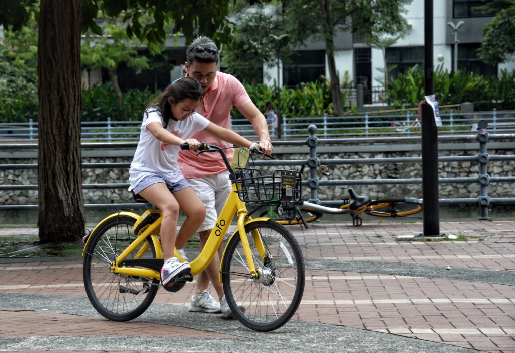 Father teaching daughter to ride a bike.